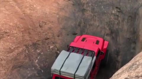 Red jeep car stuck in a ditch tries to get out by driving