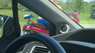 Shirtless Man Moseys Down Highway on Motorcycle