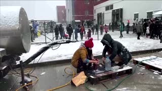 Migrants in Belarus queue in the snow for food