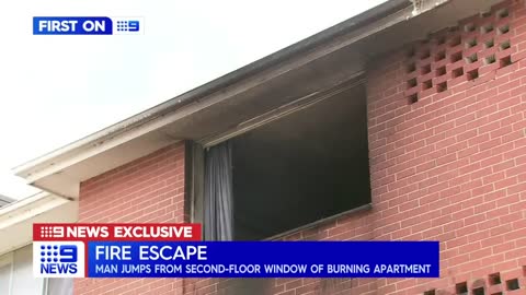Man clinging to burning apartment building