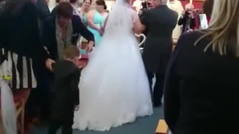 Niño se zambulle sobre el vestido de una novia durante la ceremonia