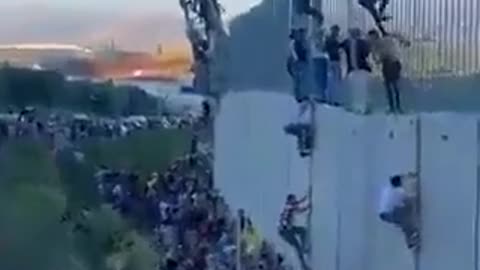 Lebanese people climbing the Israeli barrier