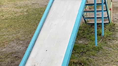Toddler Slides down Playground Slide and Splashes Into Muddy Puddle Below