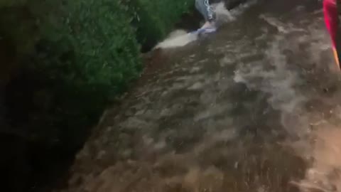 Guy surfing in flood waters pulled by car