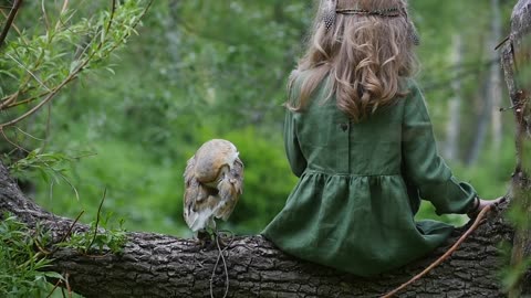 Little girl with an owl in a fairy forest. Friends