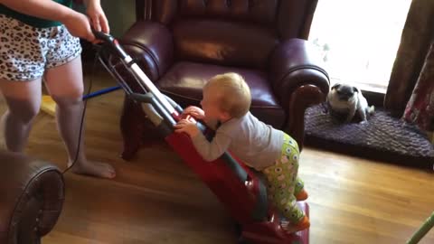 Baby "helps" mom vacuum the house