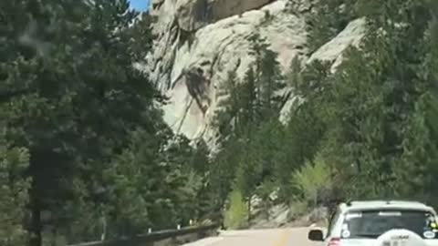 People driving see a man slack lining across two mountains in Mt Rushmore.