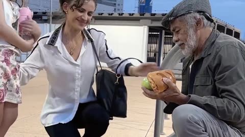 A mother and daughter extend a helping hand to a homeless man