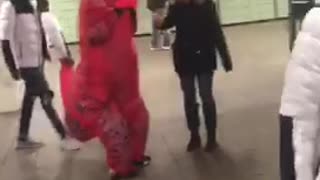 Red trex dinosaur walking through subway station