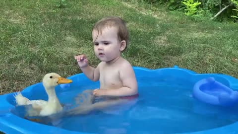 Cute baby and duck taking bath together
