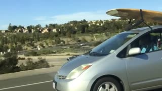 Yellow surfboard on silver prius