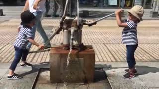Cute kids playing with an old water pump