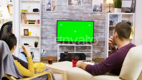 Pasangan menonton TV layar hijau dan makan popcorn