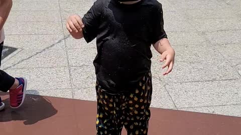 A baby playing in the water fountain.