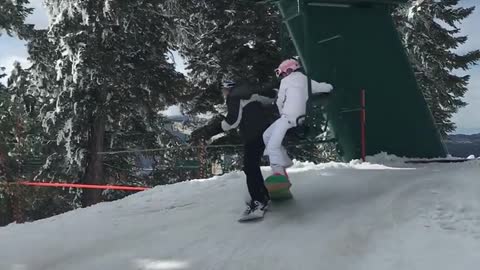 Man and woman fall on top of each other off ski lift