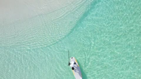 A man paddling on a board near the seashore