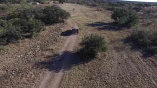 Drone following a military style hummer on a dirt road.