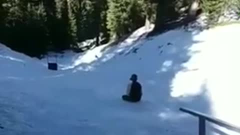 Guy slides on rail with snowboard falls off and board slides down hill