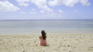 A girl sitting on the beach .