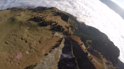 Wingsuit flying and paragliding over sea of clouds