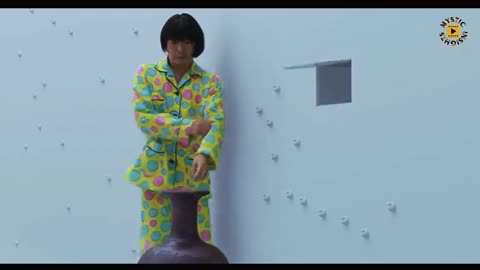 Japanese man locked in an unfurnished room, the walls adorned with an array of random button