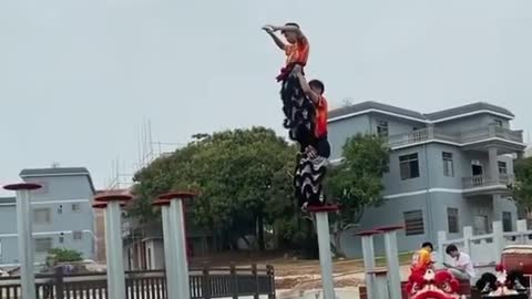 Two Dancers Practice Traditional Chinese Lion Dance Over Poles in Water