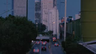 avenue with trees buildings and fast cars at dusk