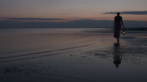 Woman walking on beach with lantern