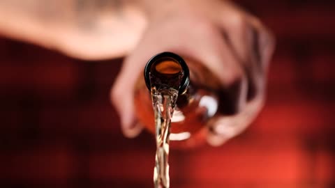 Person pouring beer from a glass bottle