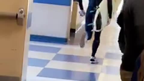 Man black wet suit runs with surf board in hallway