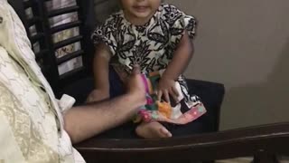 Cute baby girl is pressing her legs and singing song