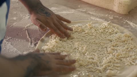 Chef tossing grated cheese on a pizza