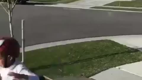 White shirt helmet kid rides bike off ramp screams on sidewalk