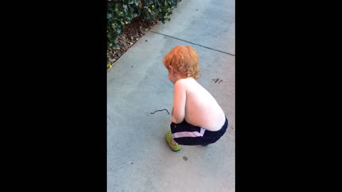 Tiny blonde boy makes friends with a worm