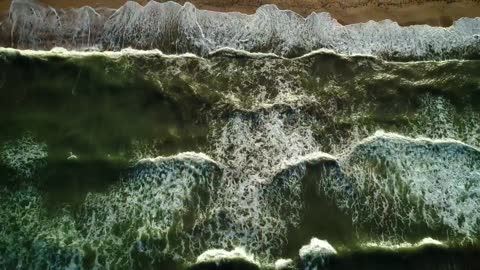 Sea waves in green tones reaching the beach