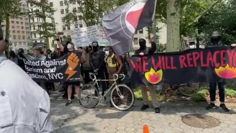 Mostly White Extremist Group Holds Sign "we will replace you," w/ Nazi collaborator flag