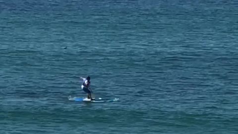 Guy tries to stand on a surfboard and he falls off