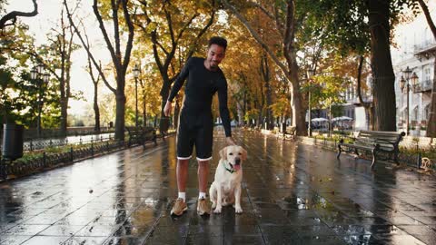 Portrait of young black man and his white labrador dog in city park during beautiful autumn morning