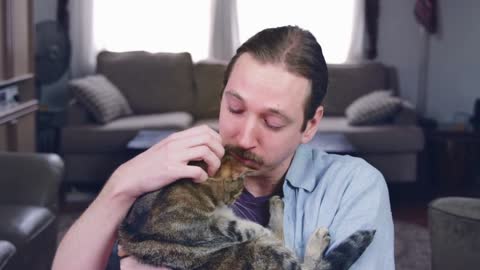 A caucasian man coughs into his elbow and cuddles a cat - slow motion