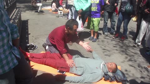 Luodong Massages Skinny Black Man On Sidewalk In Front Of Crowd
