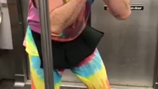 Man in tie dye outfit performs on subway