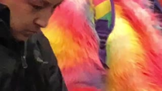 Guy in pink fur jacket has a beanie with lots of gum on it