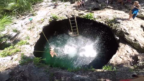 Two women jumping into a water hole.