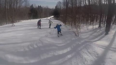 Blue jacket skier falls snow hump