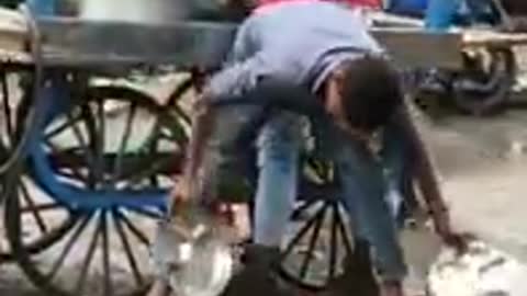 Guy washing plates in dirty water in India at food stall