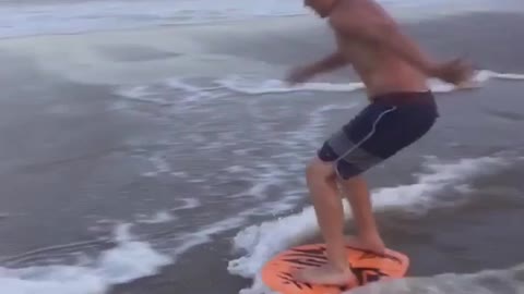 Kid orange boogie board beach shore spin fail