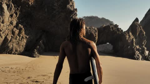 Surfer walking on the beach holding his board