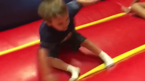 Kid spins in circle and falls over in red and blue bouncy house