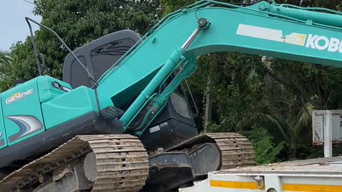 Excavator unloading machine from truck