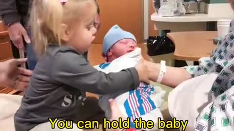Cute baby meets her newborn brother for the first time
